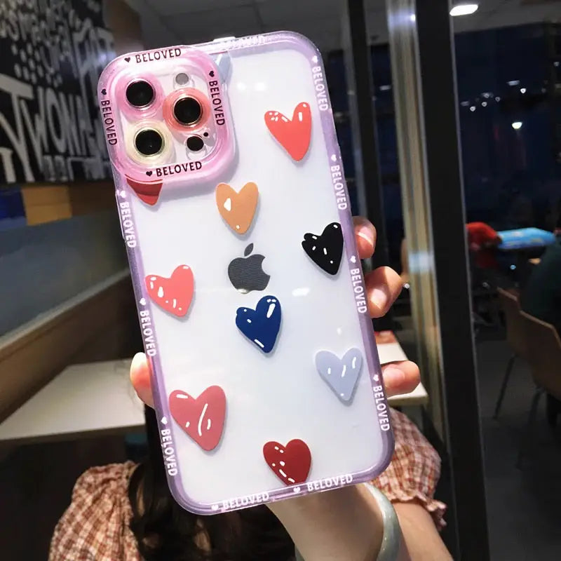 a woman holding up a phone case with heart shaped stickers