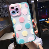 a woman holding up a phone case with colorful circles