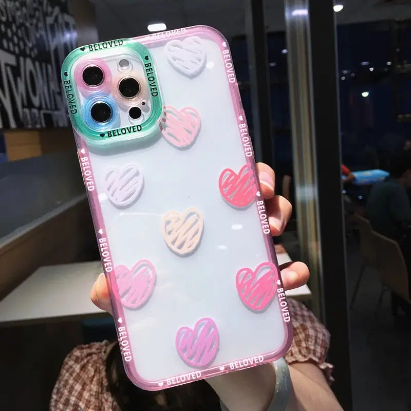 a woman holding up a phone case with pink and white heart stickers