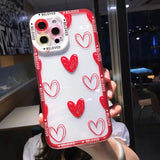 a woman holding up a phone case with red hearts on it