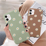 a woman holding a phone case with daisies on it