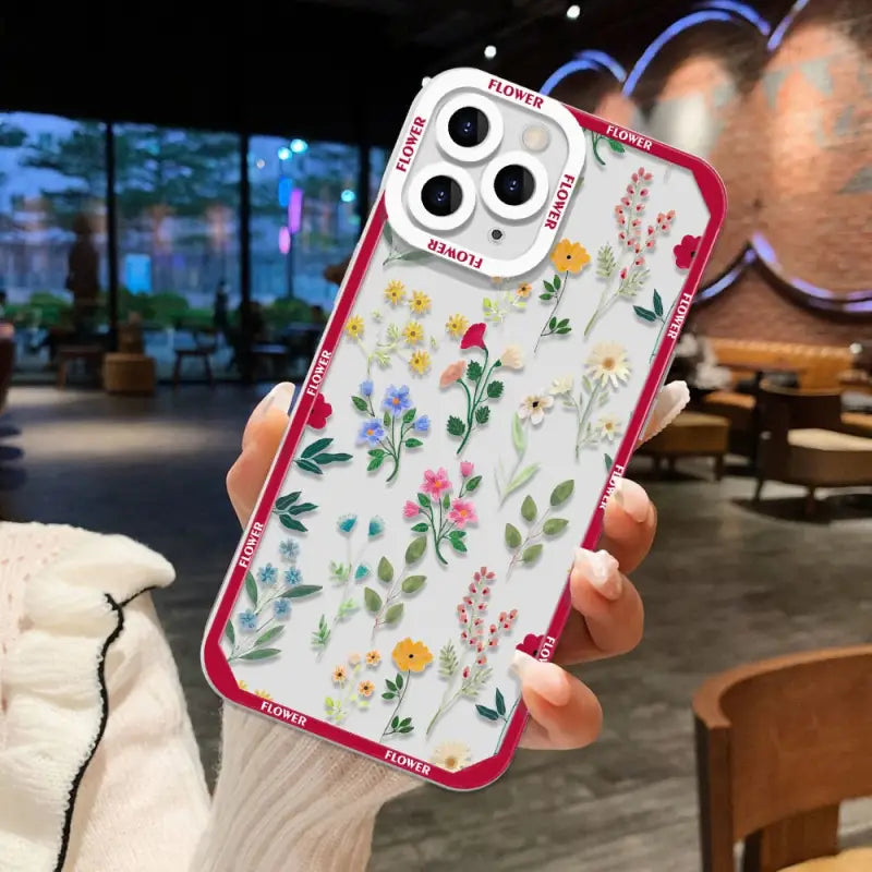 a woman holding a phone case with flowers on it