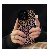 a woman holding a phone case with a leopard print