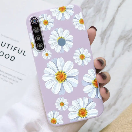 a woman holding a phone case with white flowers on it