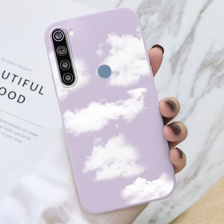 a woman holding a phone case with clouds in the sky