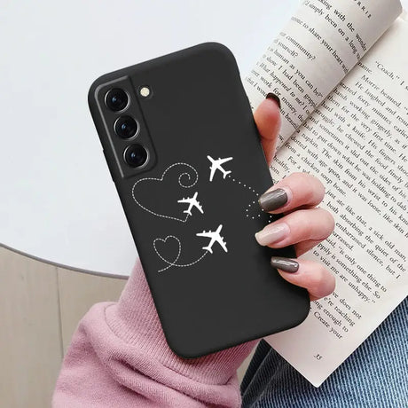 a woman holding a phone case with a plane and heart