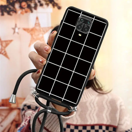 a woman holding a phone case with a black and white grid pattern