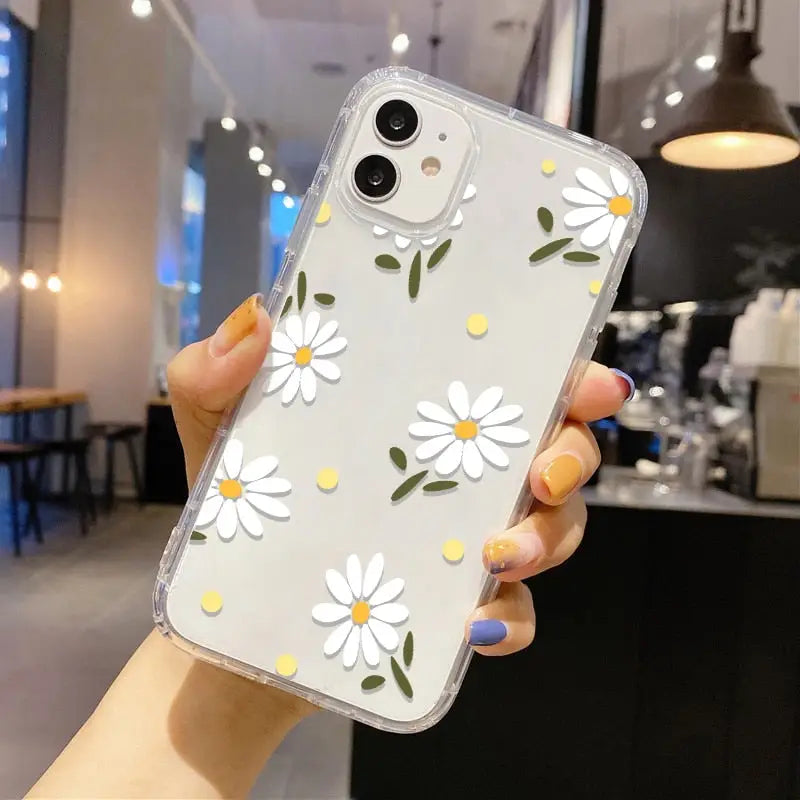 a woman holding up a phone case with white flowers on it