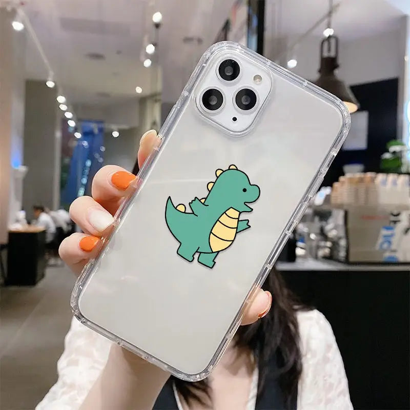 a woman holding up a phone case with a green dinosaur on it