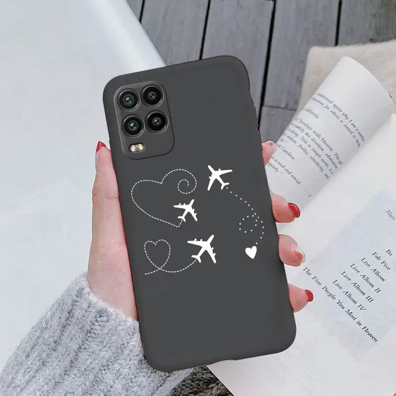 a woman holding a phone case with a plane and heart