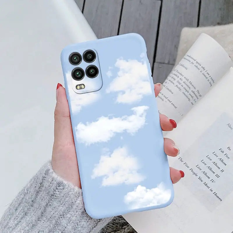 a woman holding a phone case with a blue sky and clouds pattern
