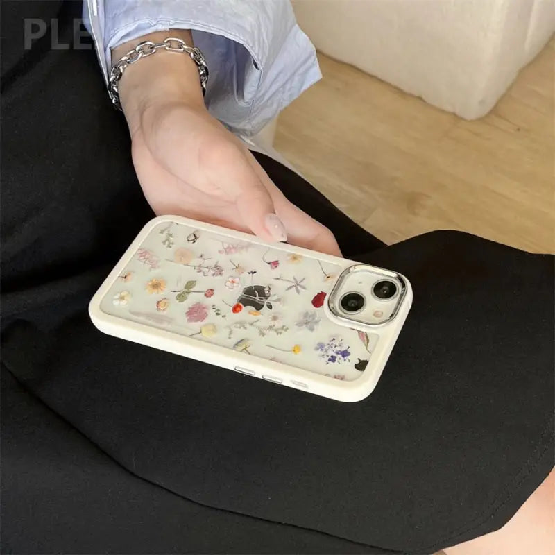 a woman is holding a phone case with flowers on it