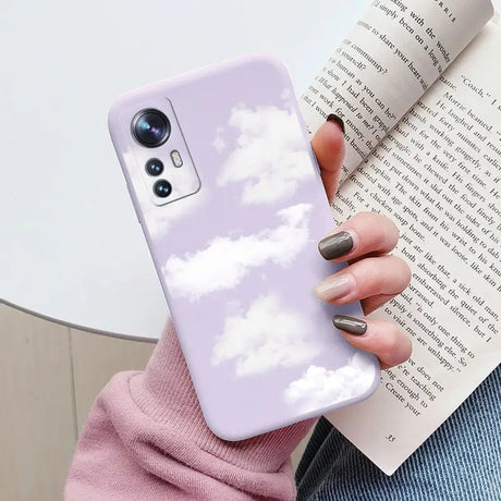 a woman holding a phone case with clouds in the sky