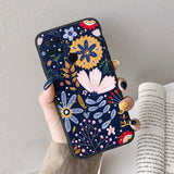 a woman holding a phone case with a floral pattern