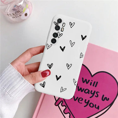 a woman holding a phone case with hearts on it