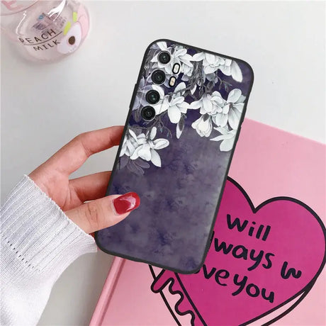 a woman holding a phone case with flowers on it