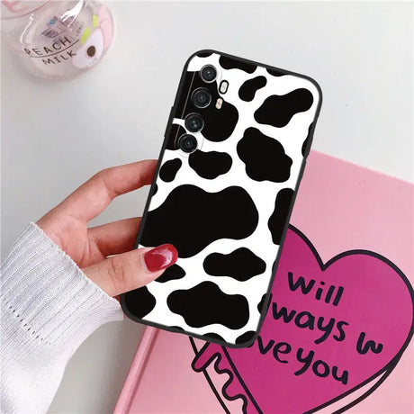 a woman holding a phone case with a cow print