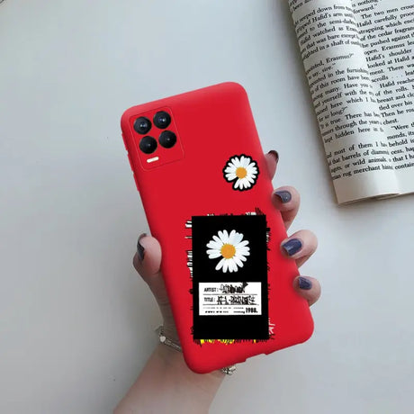 a woman holding a red phone case with a daisy on it