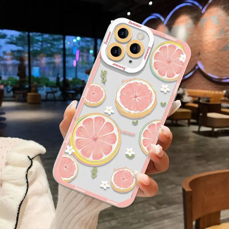 a woman holding up a phone case with a pink grape pattern