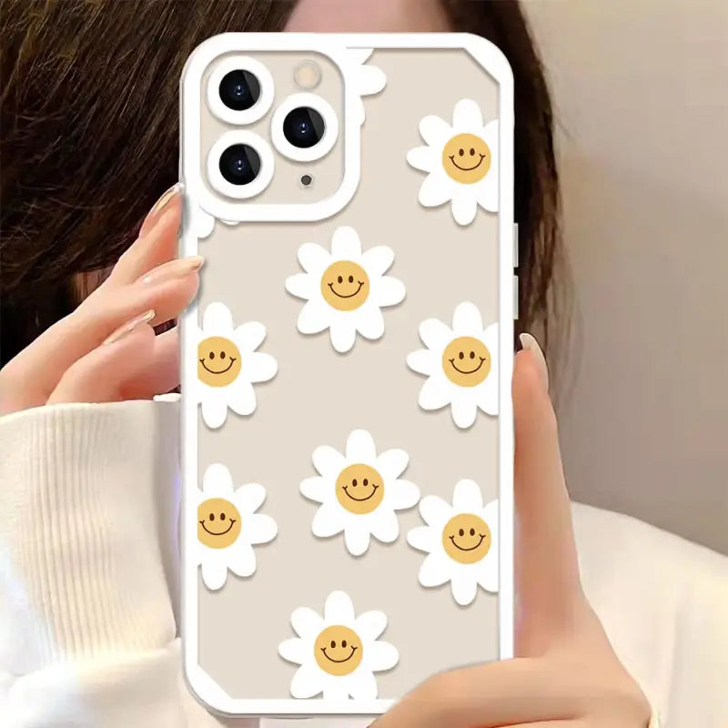 a woman holding up a phone case with smiley face