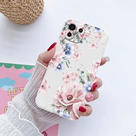 a woman holding a phone case with flowers on it