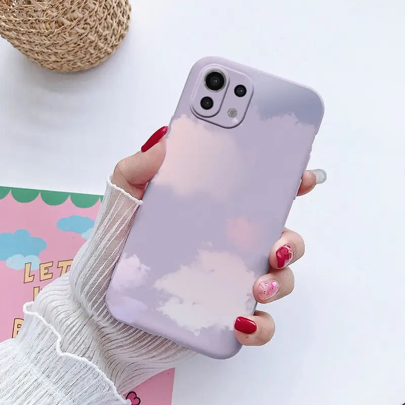 a woman holding a phone case with clouds on it