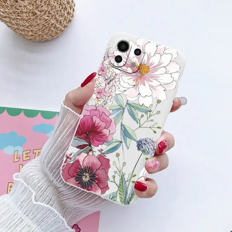 a woman holding a phone case with flowers on it