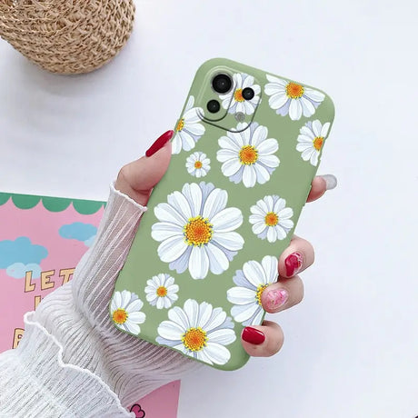 a woman holding a phone case with white flowers on it