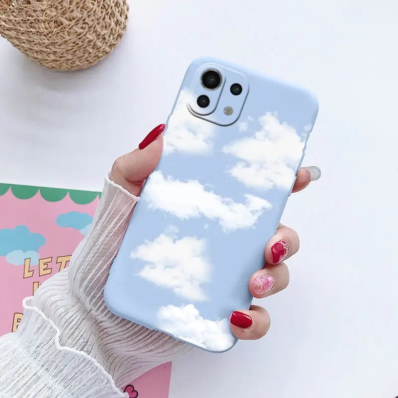 a woman holding a phone case with clouds in the sky