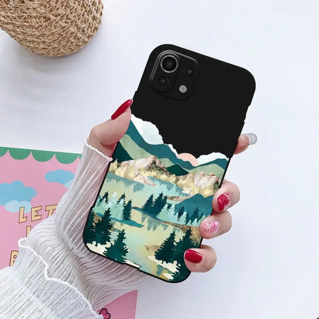 a woman holding a phone case with a mountain scene