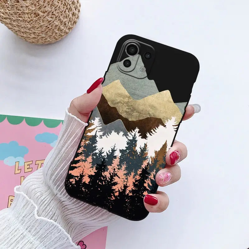 a woman holding a phone case with a mountain scene