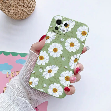 a woman holding a phone case with white flowers on it