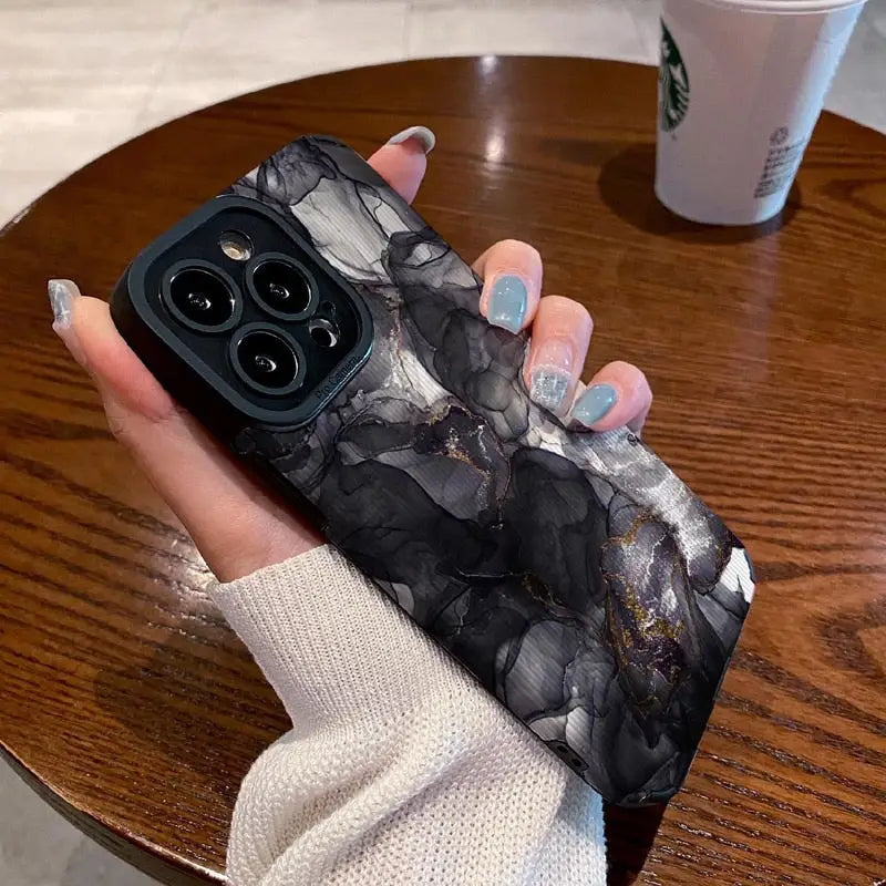 a woman holding a phone case with marble on it