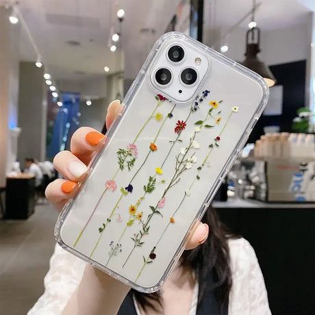 a woman holding up a phone case with flowers on it