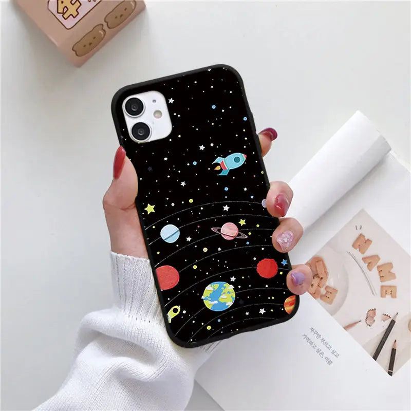 a woman holding a phone case with planets and stars