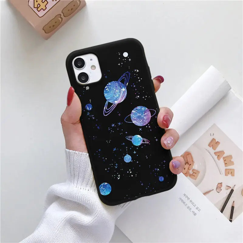 a woman holding a phone case with planets on it