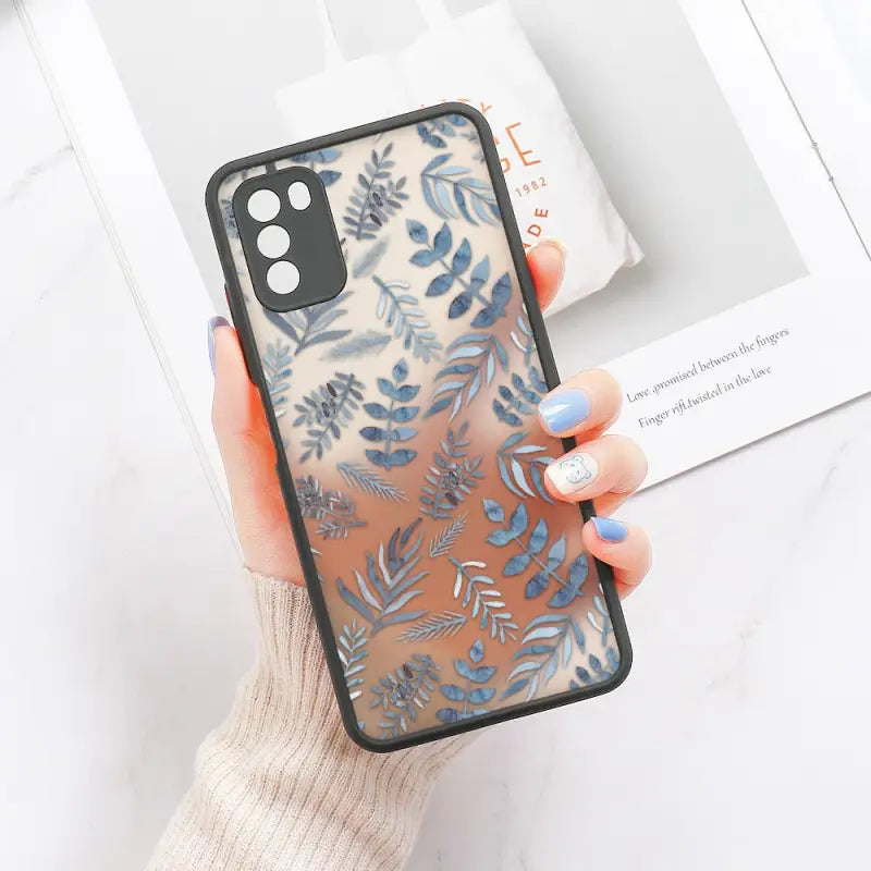 a woman holding a phone case with blue leaves on it