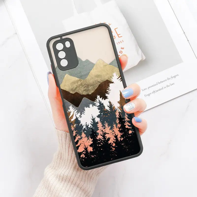 a woman holding a phone case with a mountain scene