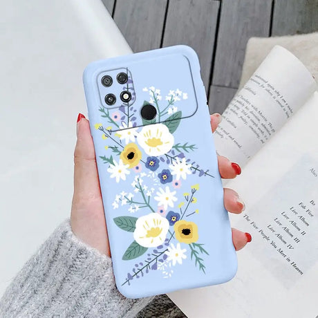 a woman holding a phone case with flowers on it