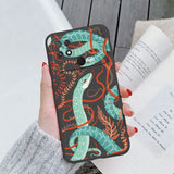 a woman holding a phone case with a green snake on it
