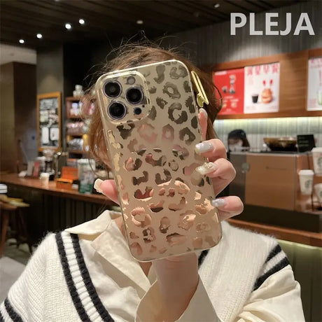 a woman holding up a phone case with a leopard print