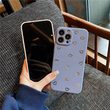 a woman holding a phone case with hearts on it