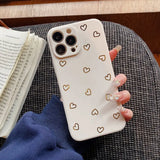 a woman holding a phone case with gold hearts on it