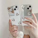 a woman holding two iphone cases with a heart