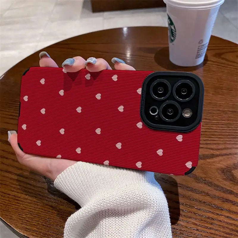 a woman holding a red phone case with white hearts on it