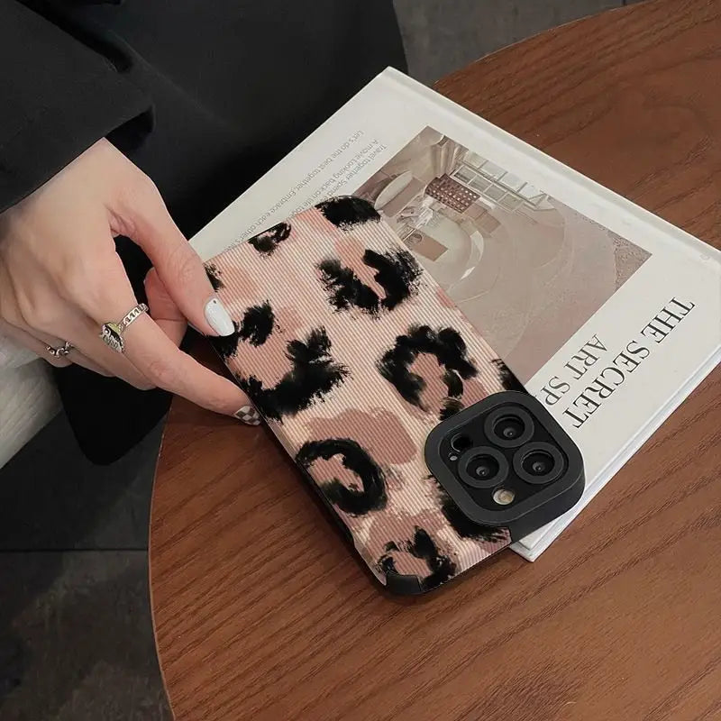 a woman holding a phone case with a black and pink flower pattern