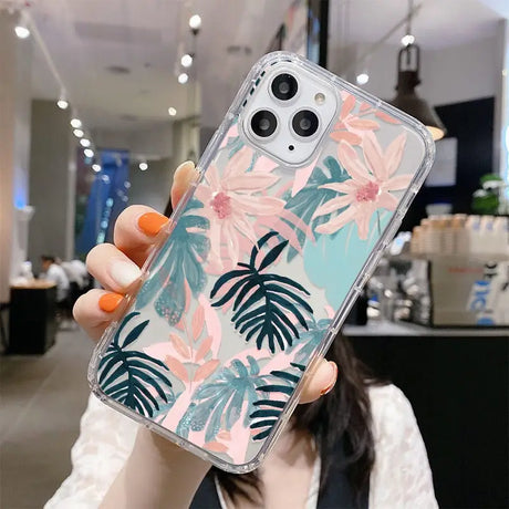 a woman holding up a phone case with a tropical print