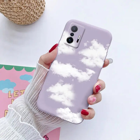 a woman holding a phone case with clouds on it