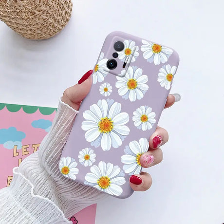 a woman holding a phone case with white flowers on it