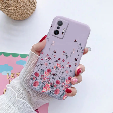 a woman holding a phone case with flowers on it